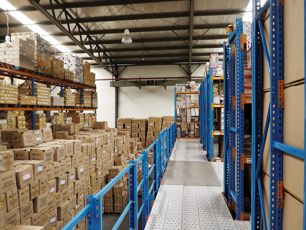 Pasillo de bodega con estantería industrial de almacenamiento.